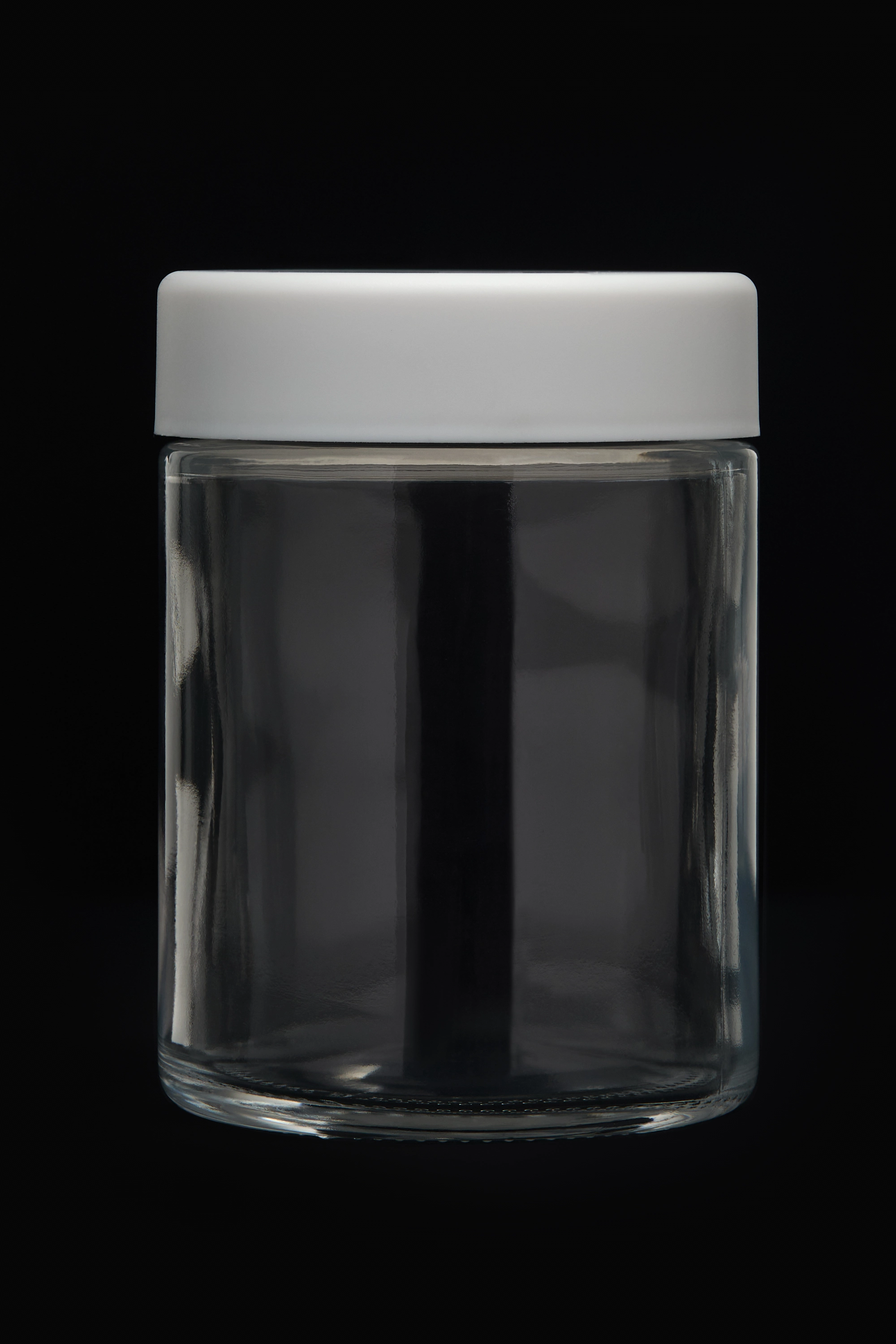 Child-resistant glass jar with white lid on dark background